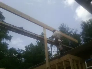 Carpenter setting a ridge beam over a new addition frame — Ice Dam Removal by Roofing Brothers in Wallula