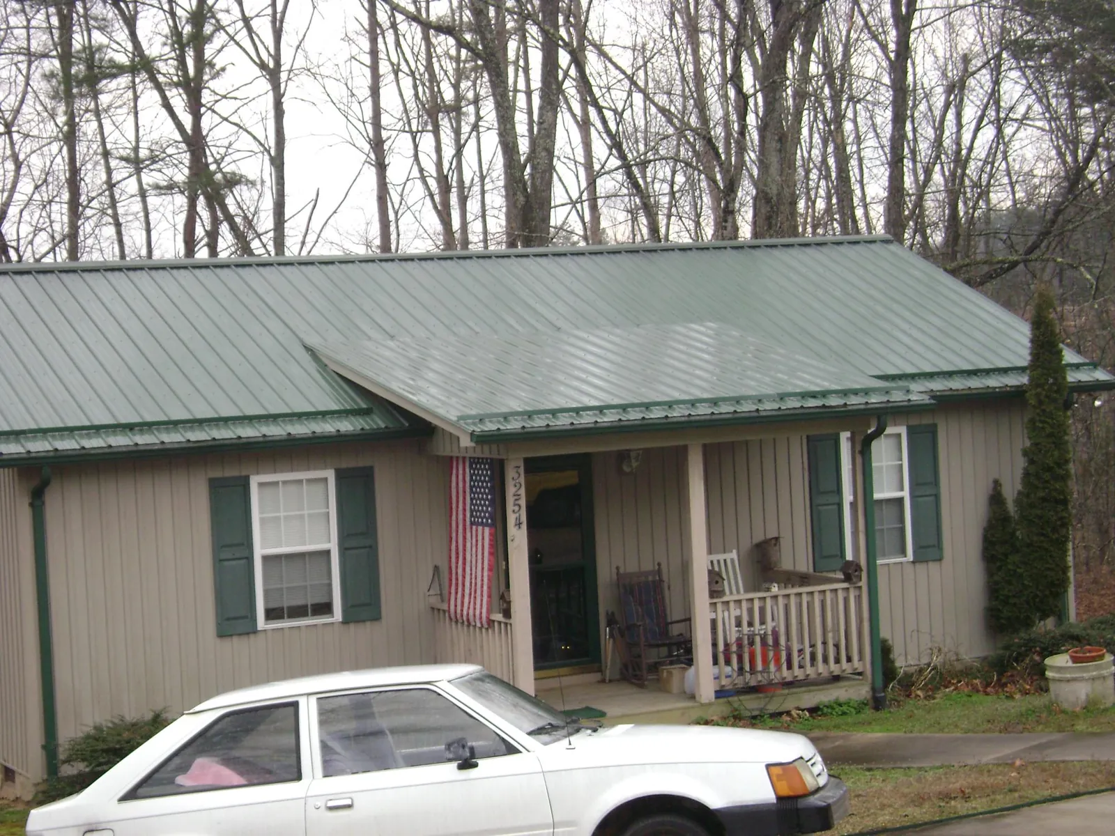 Green metal roof and front porch on a tan sided cottage in Wallula