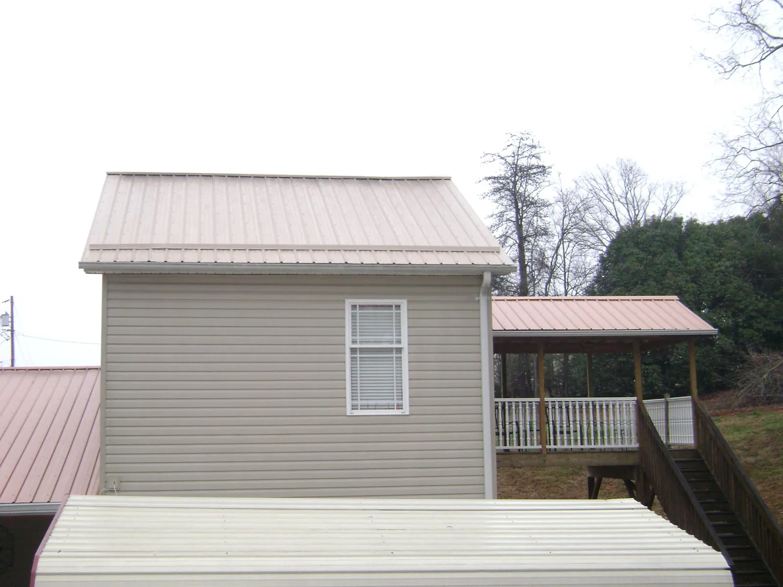 Tan metal roofs on a two story addition and attached porch, from a Roof Replacement job in Wallula