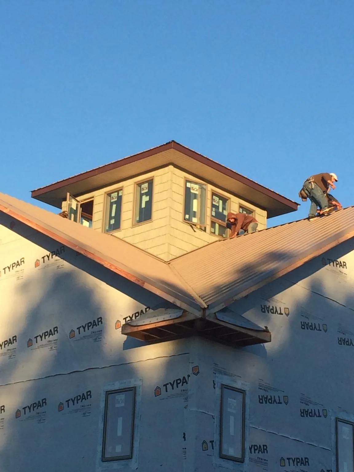 Roofers working around a rooftop cupola on a new metal roof at sunset — Roof Waterproofing in Wallula by Roofing Brothers